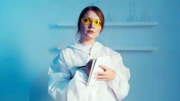 Woman in White Dress Shirt Wearing Yellow Sunglasses Holding White Book