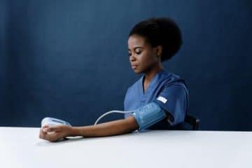 A Healthcare Worker Measuring Her Own Blood Pressure Using a Sphygmomanometer: Complete Guide to Becoming A Nurse Practitioner