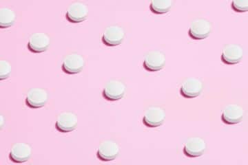 White Round Capsule on Pink Background Close-up Photography
