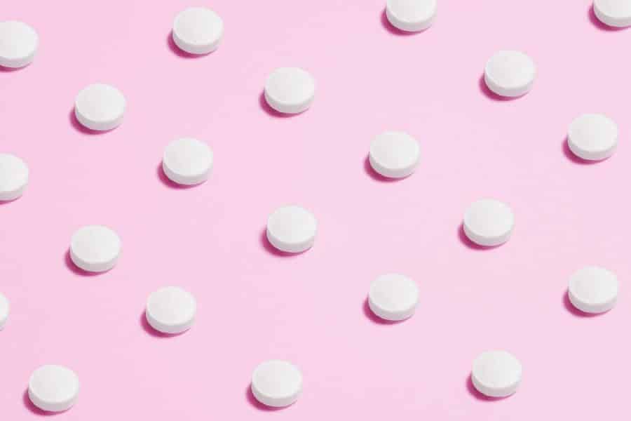 White Round Capsule On Pink Background Close-Up Photography