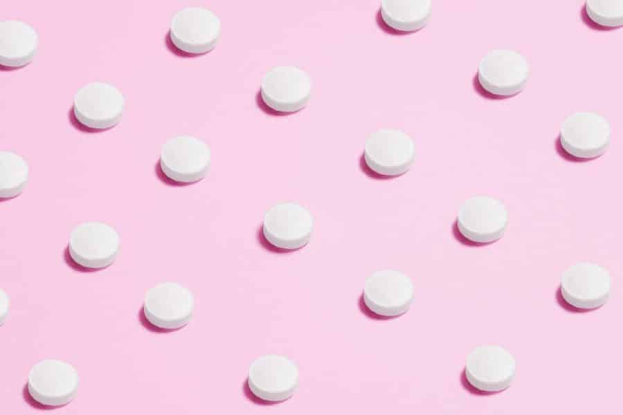 White Round Capsule on Pink Background Close-up Photography