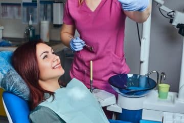 Free photo a young redhead woman having examination while sitting in a dental chair in the clinic.