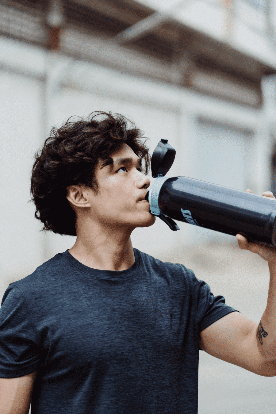 A Man Drinks Water From A Water Bottle.